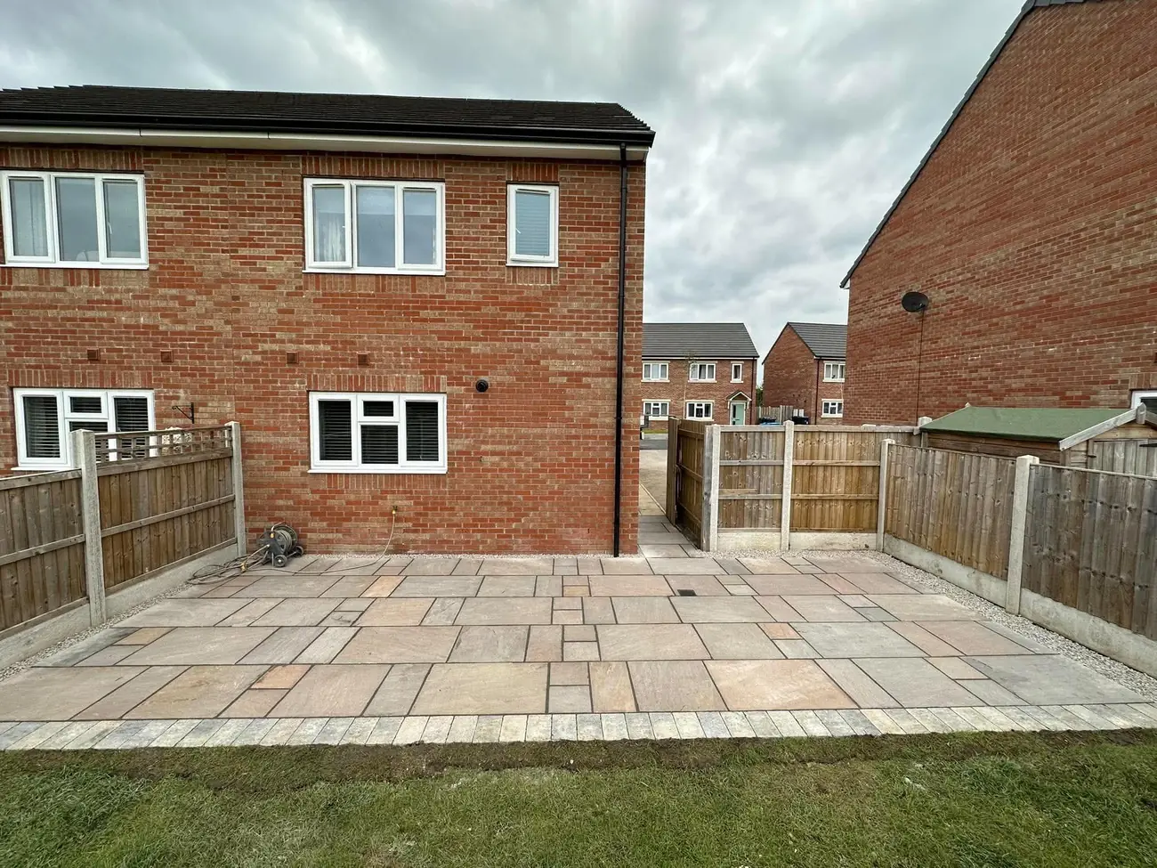 Indian stone patio with block edging and gravel margins behind a brick house