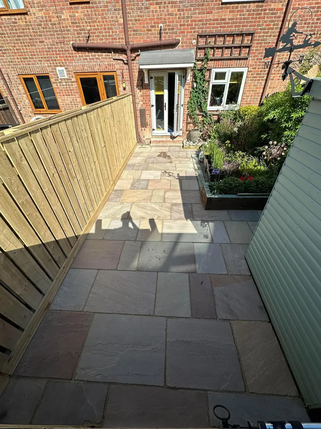 Indian stone path beside a new close-board fence leading to a house door