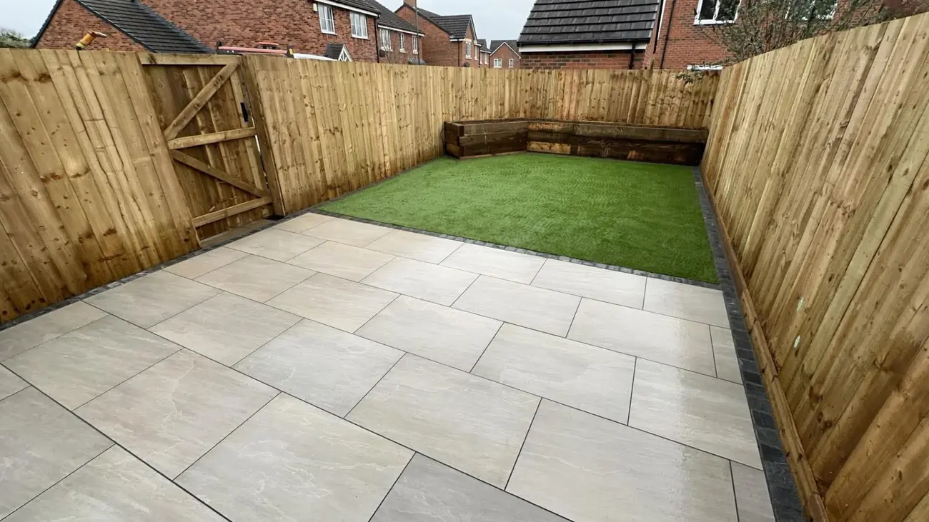 Porcelain patio with artificial grass and a corner sleeper bed inside new fencing
