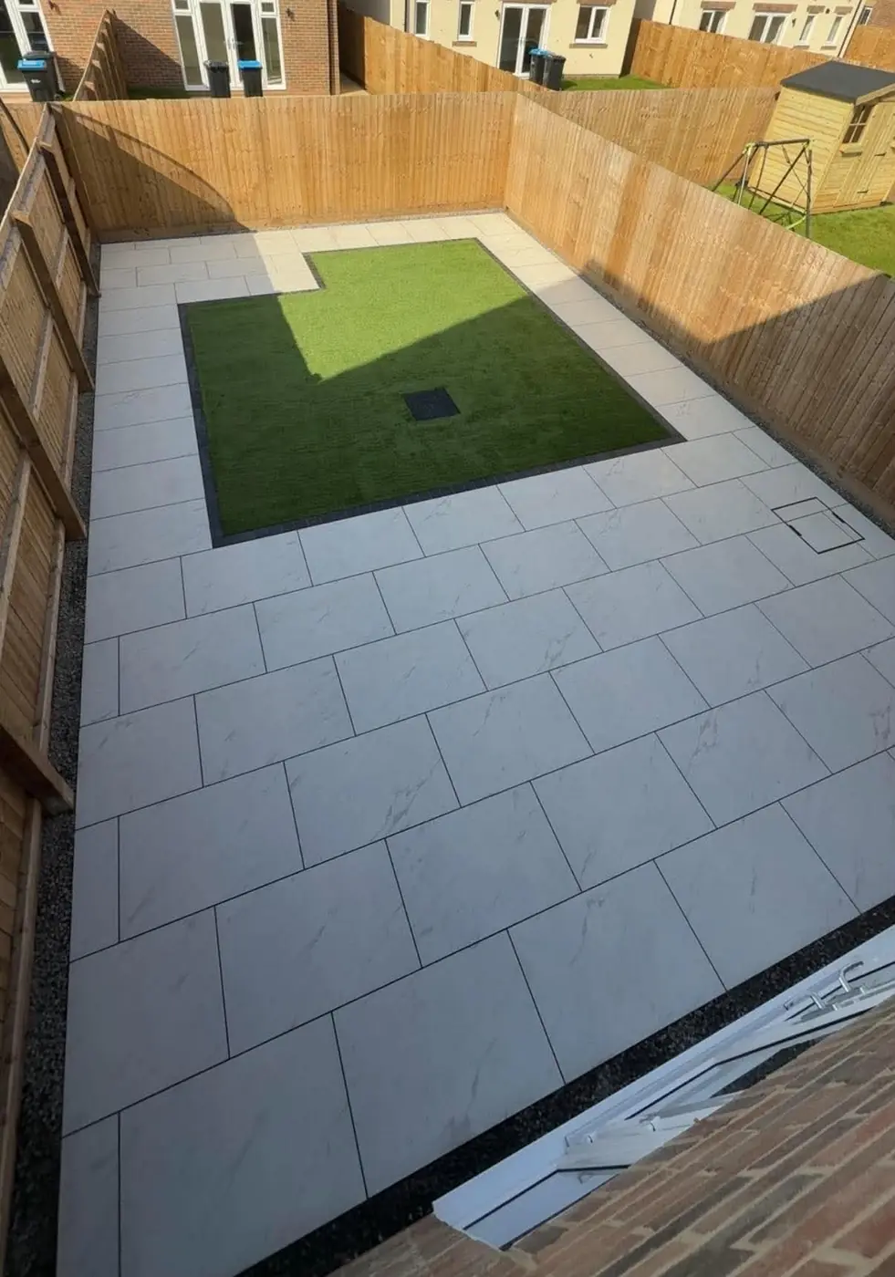 Aerial view of a marble-look porcelain patio with an artificial grass inset