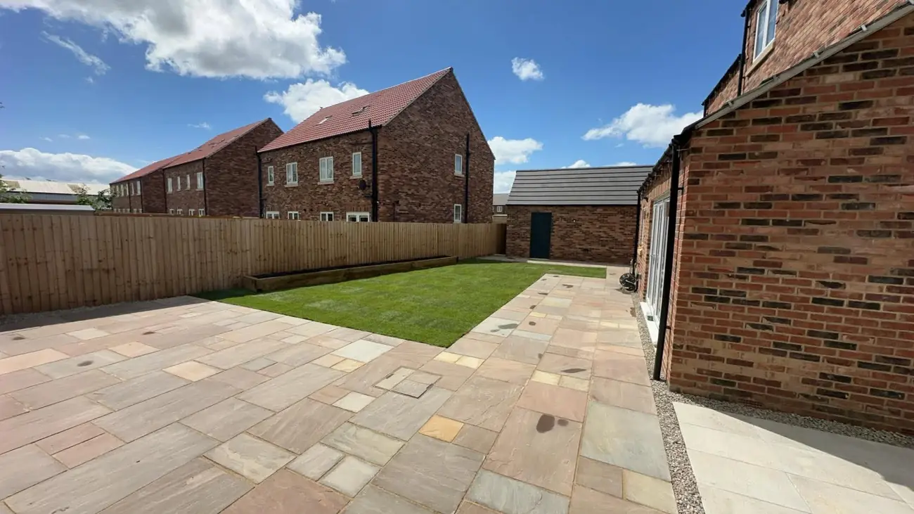 Indian stone patio and lawn with a raised sleeper bed along the fence