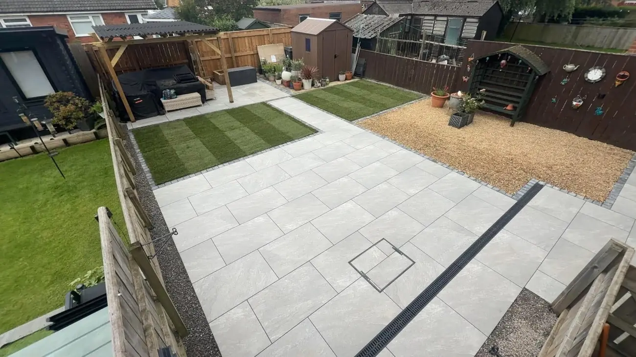 Light porcelain patio with two lawn areas, a gravel bed, a drainage channel and a pergola seating area