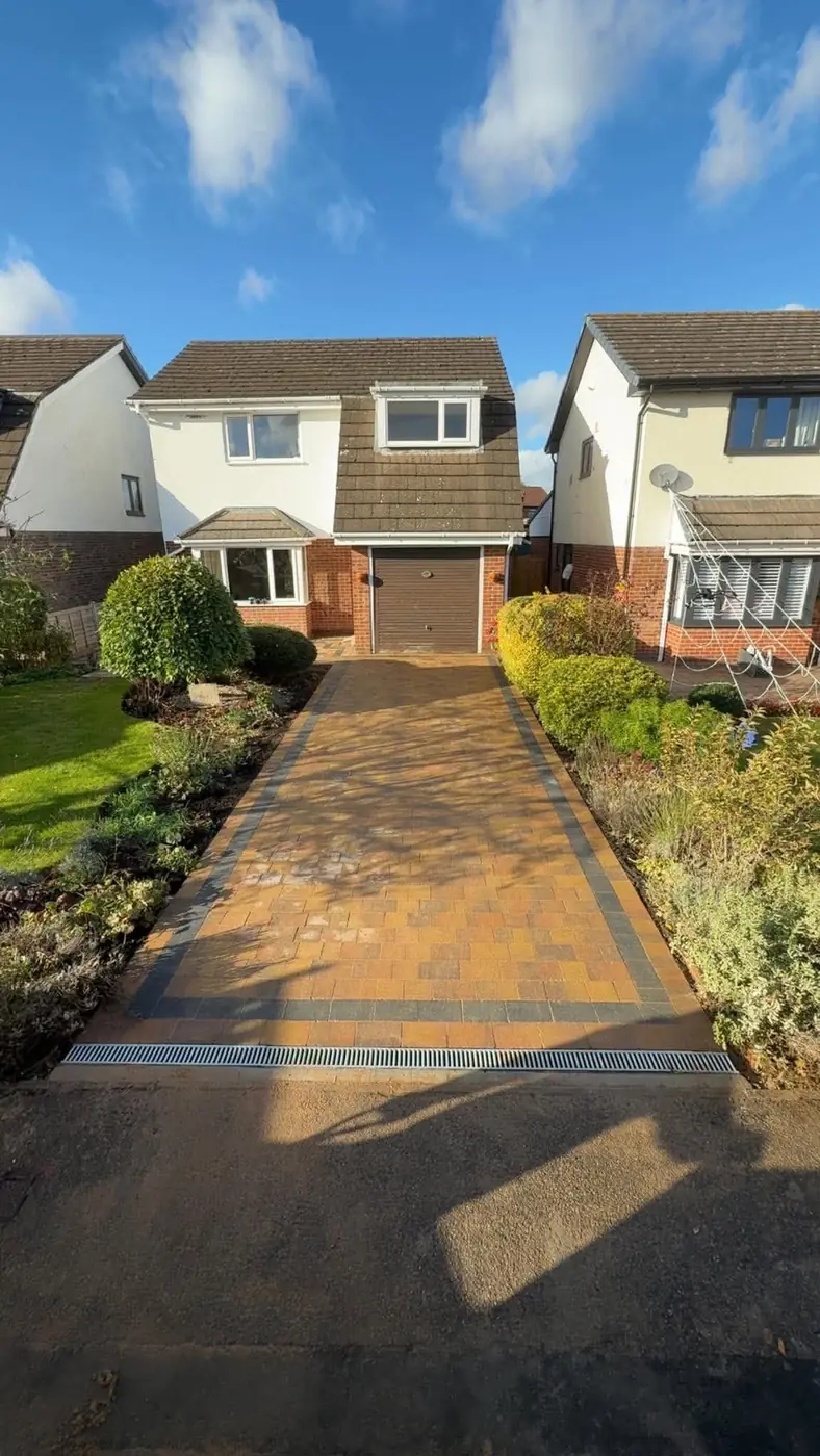 Block paving driveway with a grey border and a drainage channel at the road