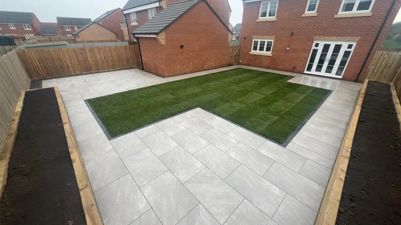 Porcelain patio around a turf lawn with raised sleeper beds either side